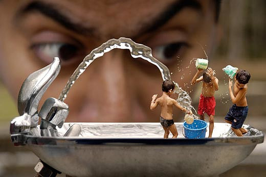Miniature children playing in a drinking fountain